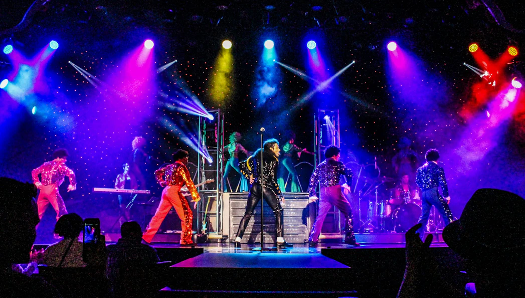 Stage performance of MJ Live in Vegas with dancers in colorful costumes.