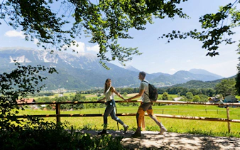 Couple walking on a scenic trail near Vintgar Gorge with mountains in the background, Bled.
