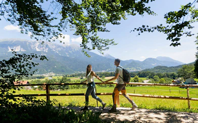 Couple walking on a scenic trail near Vintgar Gorge with mountains in the background, Bled.