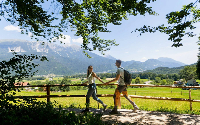 Couple walking on a scenic trail near Vintgar Gorge with mountains in the background, Bled.