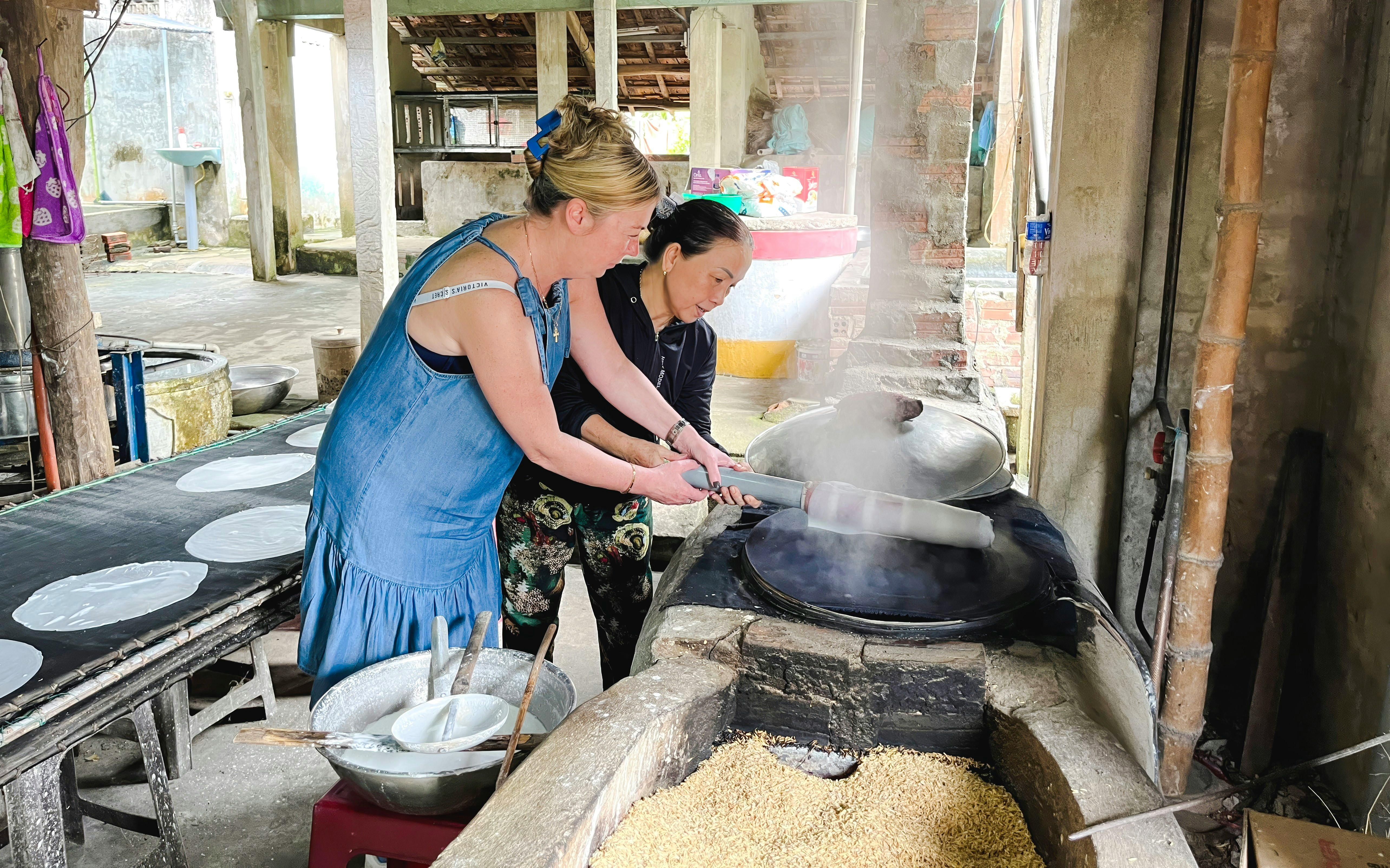Women making rice paper in a traditional Vietnamese workshop.