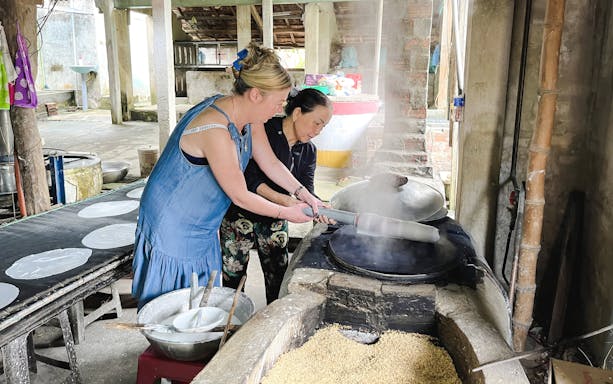 Women making rice paper in a traditional Vietnamese workshop.