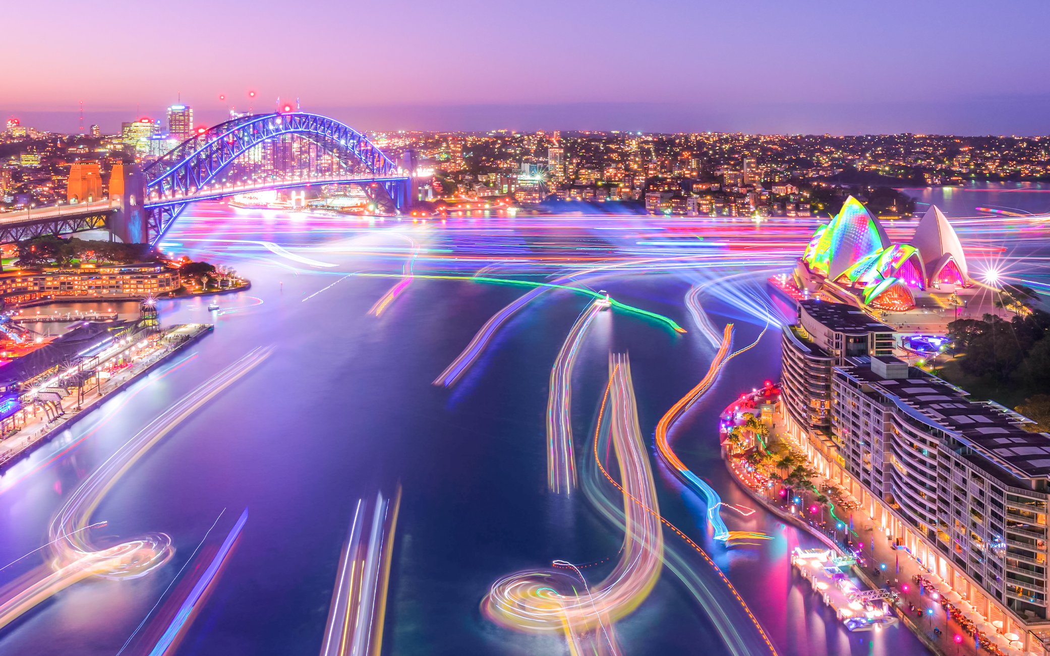 Sydney Harbour Bridge and Opera House illuminated during Vivid Sydney cruise.