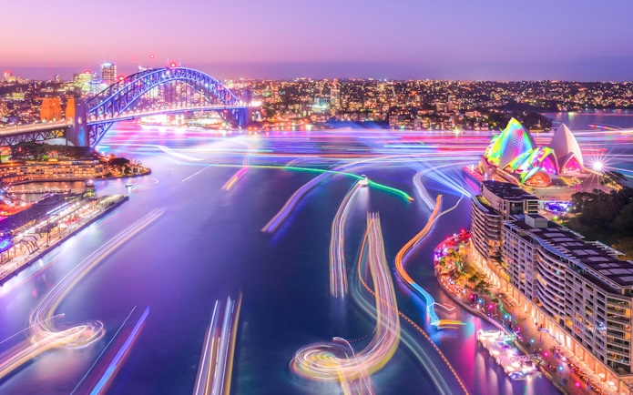 Sydney Harbour Bridge and Opera House illuminated during Vivid Sydney cruise.