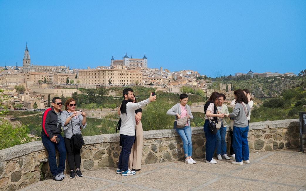 Tourists taking photos at Mirador del Valle viewpoint in Toledo, Spain.