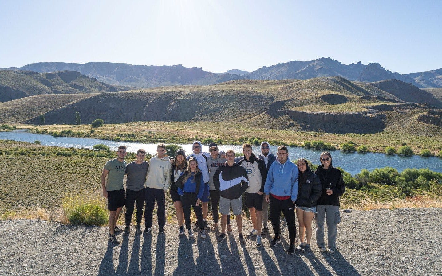 Visitors at a scenic viewpoint overlooking Patagonian landscapes with mountains and river.