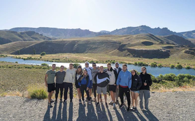 Visitors at a scenic viewpoint overlooking Patagonian landscapes with mountains and river.