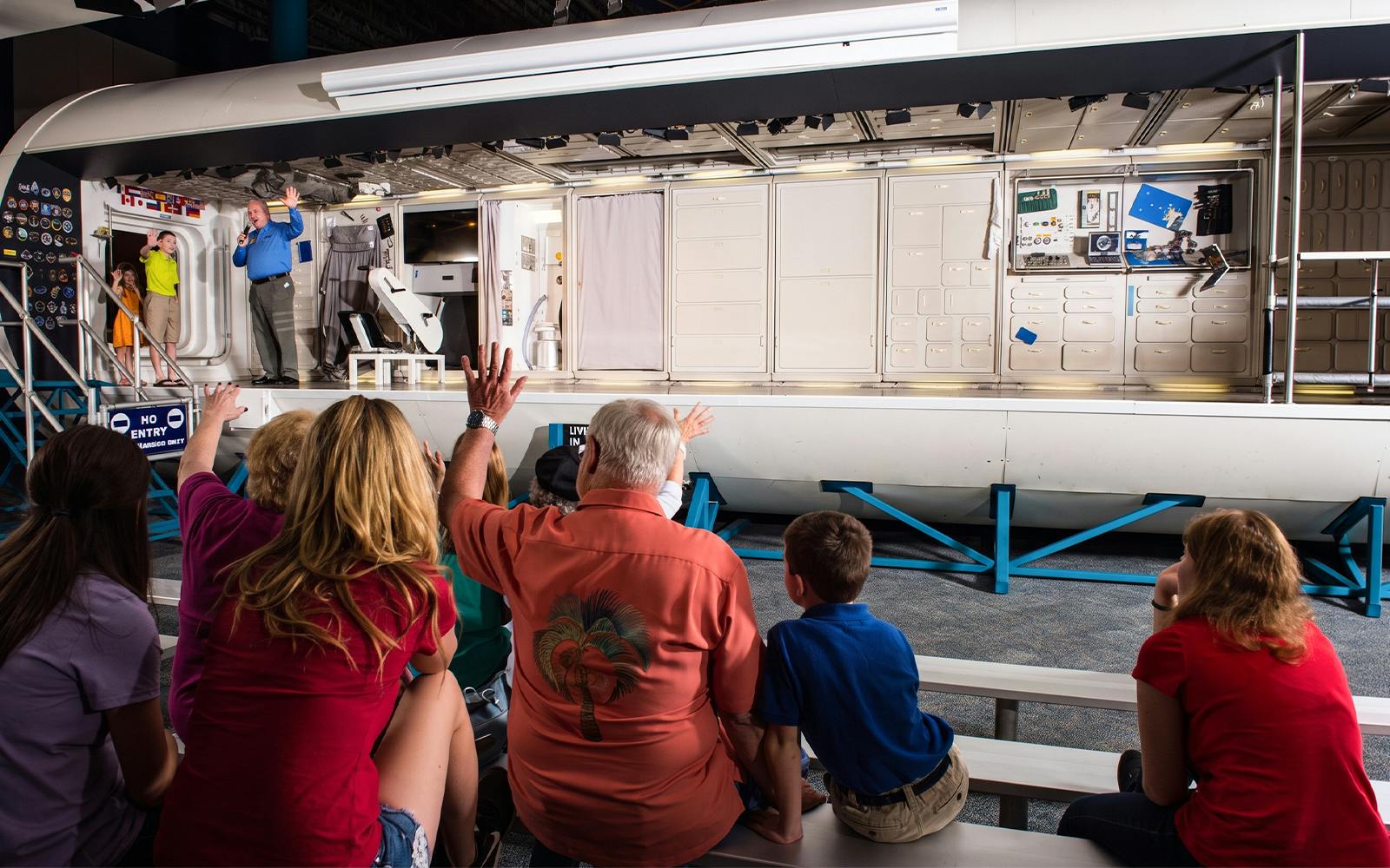 Audience watching a presentation inside a space module at Space Center Houston.