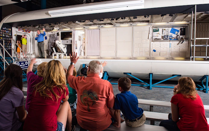 Audience watching a presentation inside a space module at Space Center Houston.