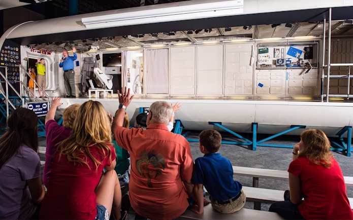 Audience watching a presentation inside a space module at Space Center Houston.