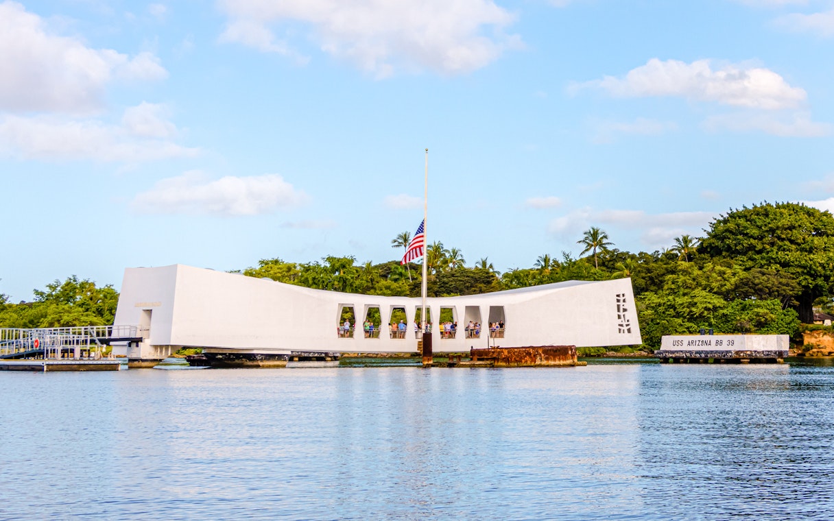 USS Arizona Memorial on Pearl Harbor, Oahu, Hawaii, with visitors and American flag.