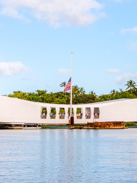 USS Arizona Memorial on Pearl Harbor, Oahu, Hawaii, with visitors and American flag.