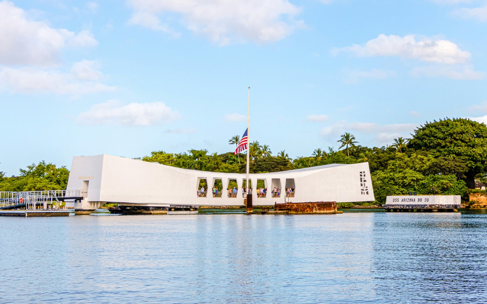 USS Arizona Memorial on Pearl Harbor, Oahu, Hawaii, with visitors and American flag.