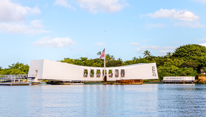 USS Arizona Memorial on Pearl Harbor, Oahu, Hawaii, with visitors and American flag.