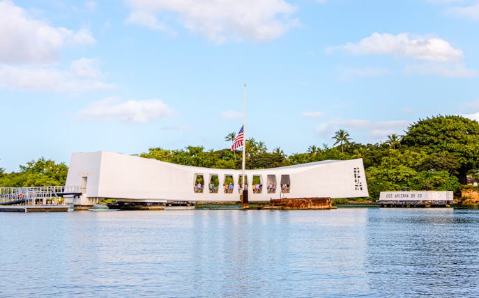 USS Arizona Memorial on Pearl Harbor, Oahu, Hawaii, with visitors and American flag.