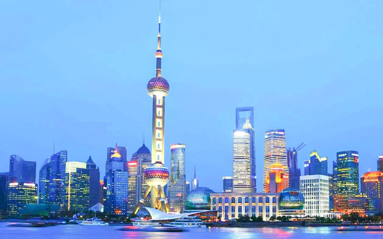 Oriental Pearl Tower in Shanghai's Pudong district with city skyline at dusk.