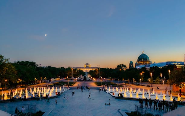 Berlin Lights Festival at dusk with illuminated fountains and cityscape.