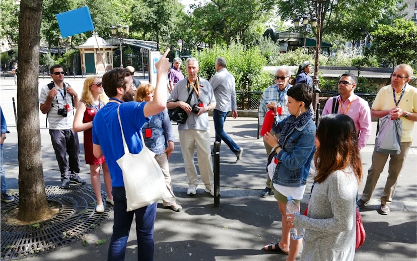 Tour guide leading a group of tourists in a Paris park, France.