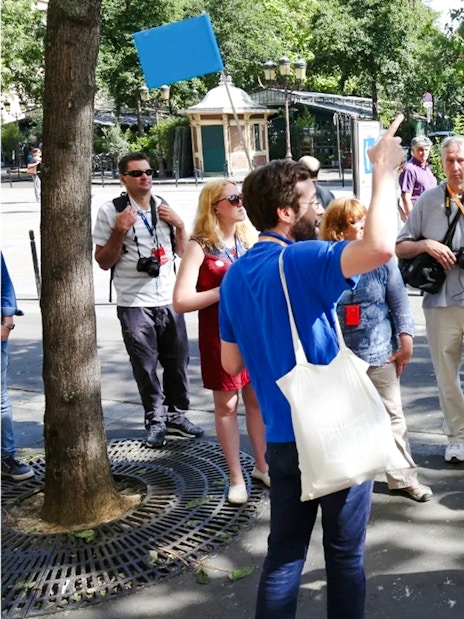 Tour guide leading a group of tourists in a Paris park, France.