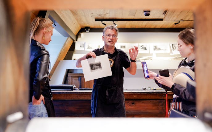 Guide explaining artwork inside Rembrandt House Museum, Amsterdam.