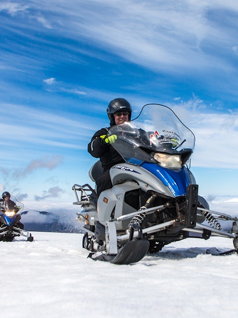Snowmobile ride on Langjokull Glacier under clear blue sky.