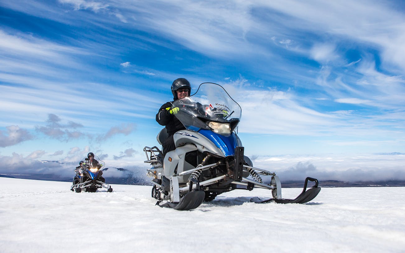Snowmobile ride on Langjokull Glacier under clear blue sky.