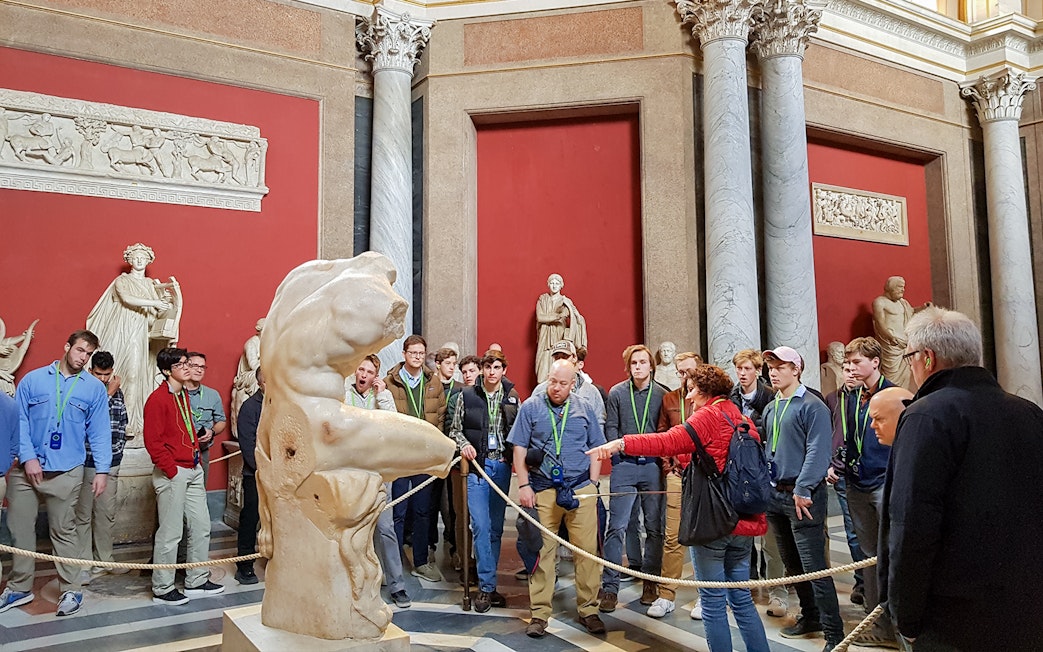 Tour group observing ancient sculptures in the Vatican Museums.