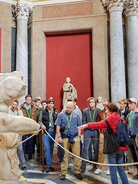 Tour group observing ancient sculptures in the Vatican Museums.