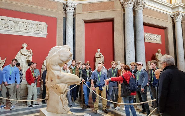 Tour group observing ancient sculptures in the Vatican Museums.