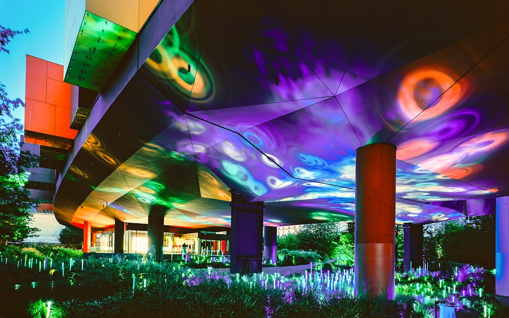 Colorful light display at night under the Musee du Quai Branly in Paris.
