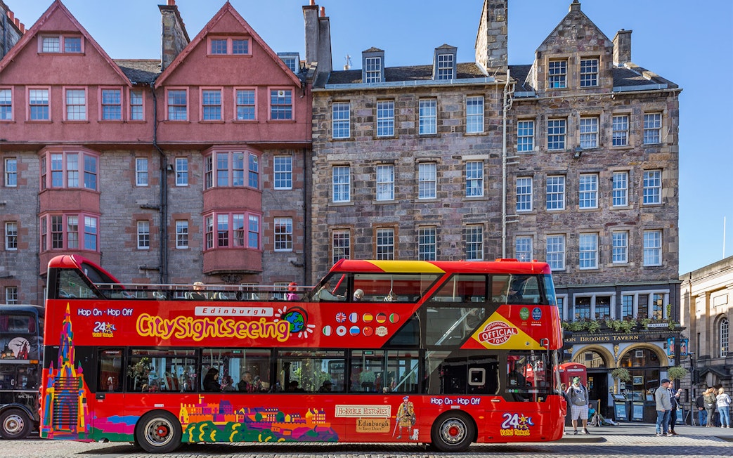 Edinburgh hop-on hop-off tour bus in front of historic buildings.