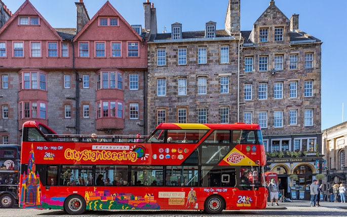 Edinburgh hop-on hop-off tour bus in front of historic buildings.