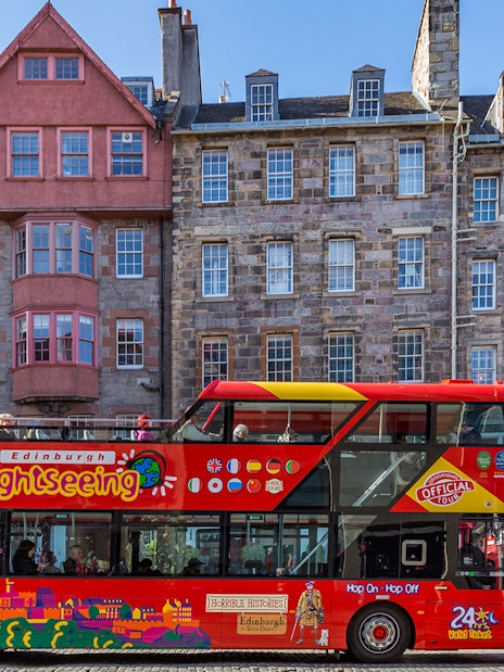 Edinburgh hop-on hop-off tour bus in front of historic buildings.