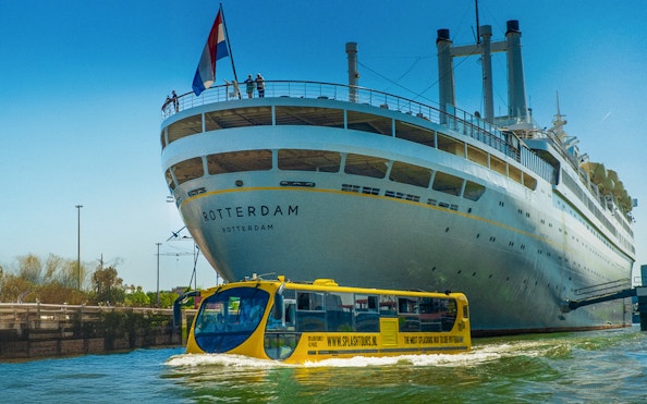 Amphibious bus touring near a large ship in Rotterdam during a 1-hour sightseeing splash tour.