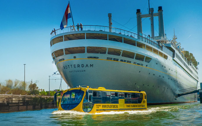 Amphibious bus touring near a large ship in Rotterdam during a 1-hour sightseeing splash tour.