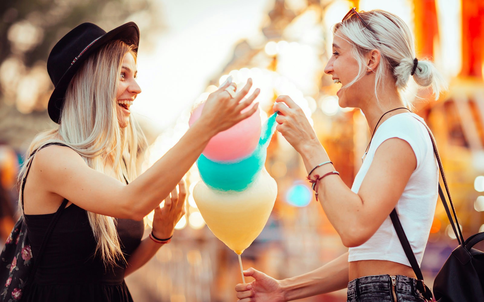 Girls enjoying cotton candy at an amusement park.