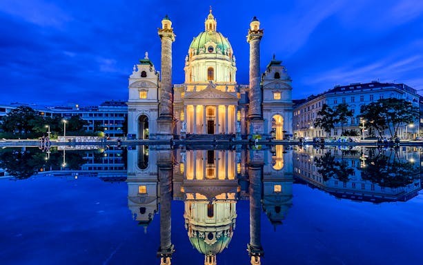 Karlskirche illuminated at night, reflecting in a pond, Vienna, part of 24/48/72-Hour QueerCityPass.