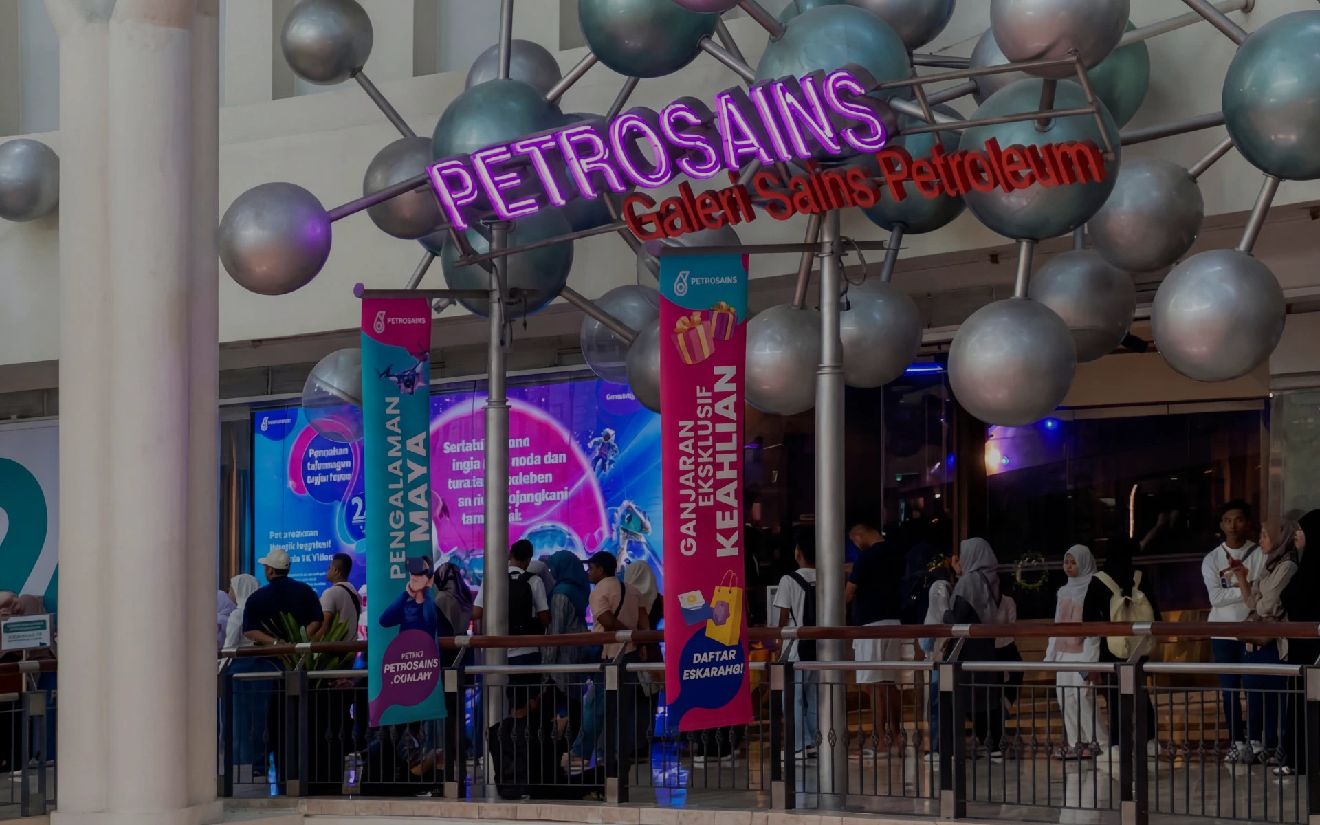 Petrosains entrance with molecule structure, Kuala Lumpur, visitors in line for exhibits.