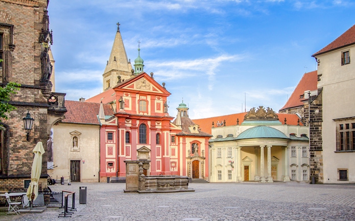 Basilica of St George exterior with red facade and courtyard in Prague.