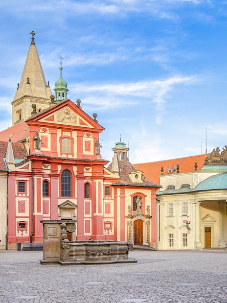 Basilica of St George exterior with red facade and courtyard in Prague.