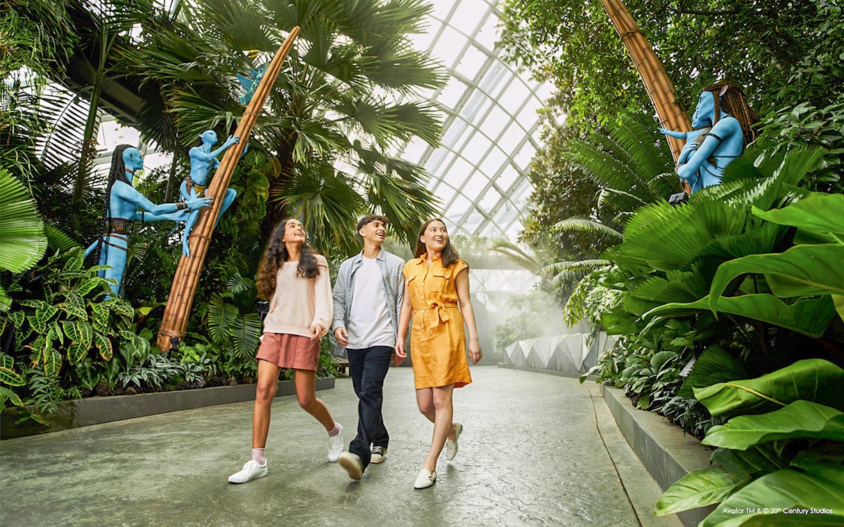 Visitors walking through lush greenery at Gardens by the Bay, Singapore, with Avatar-themed sculptures.