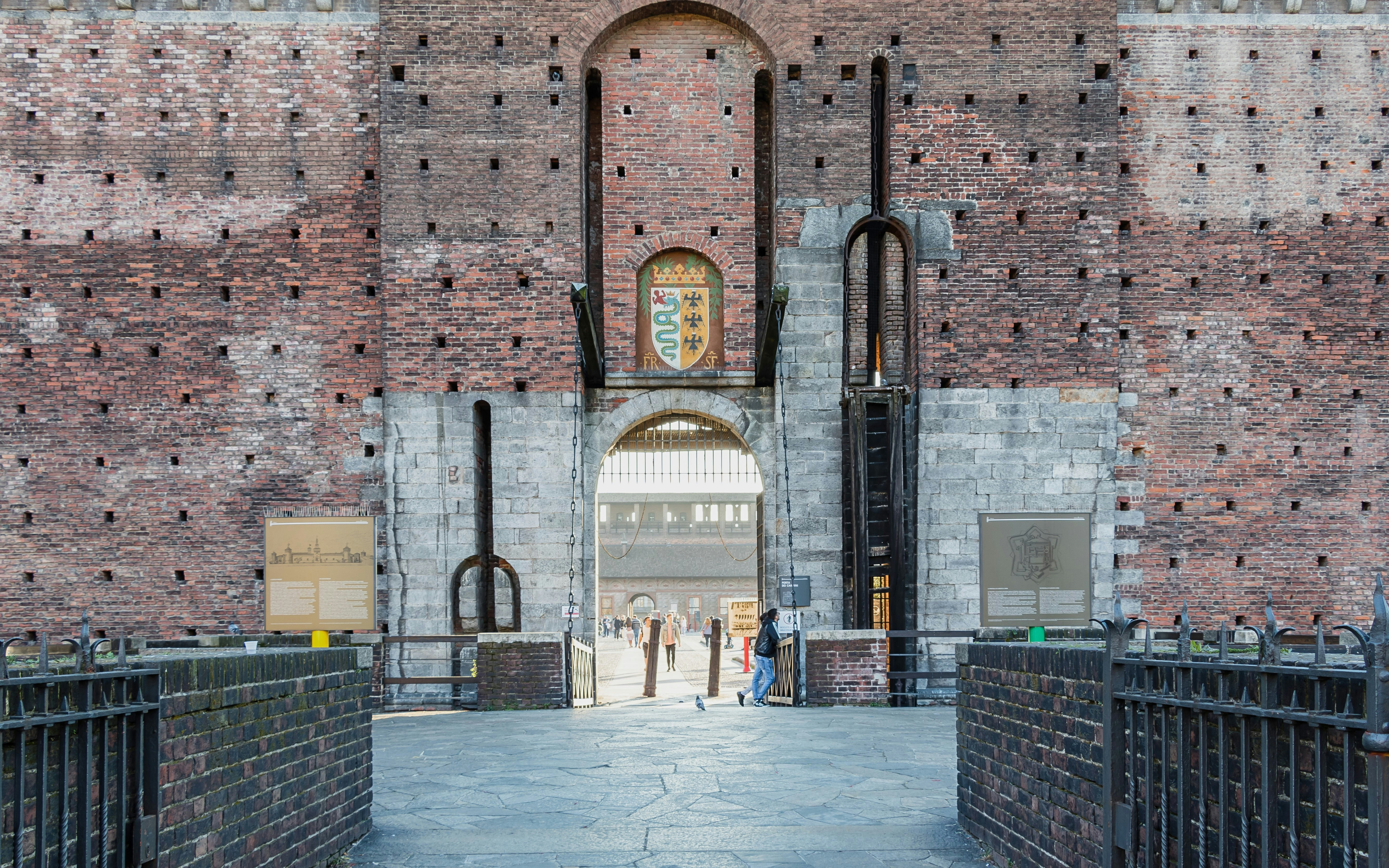 Entrance of Sforza Castle in Milan with brick walls and a central archway.