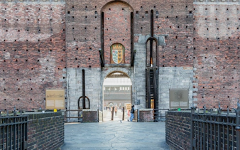 Entrance of Sforza Castle in Milan with brick walls and a central archway.