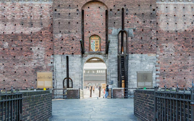 Entrance of Sforza Castle in Milan with brick walls and a central archway.