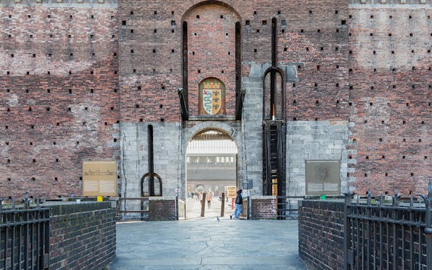 Entrance of Sforza Castle in Milan with brick walls and a central archway.