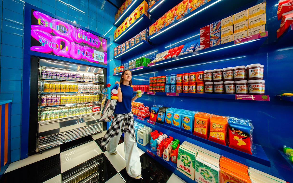 Young woman shopping in a vibrant store with colorful snacks and drinks, House Of Hype.