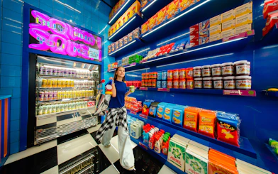 Young woman shopping in a vibrant store with colorful snacks and drinks, House Of Hype.
