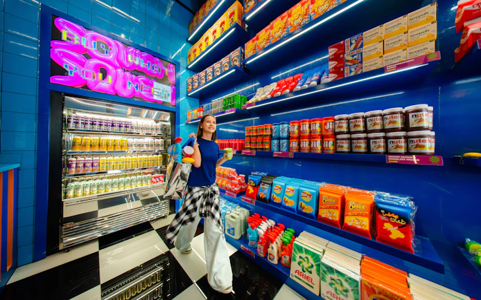 Young woman shopping in a vibrant store with colorful snacks and drinks, House Of Hype.