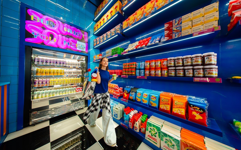 Young woman shopping in a vibrant store with colorful snacks and drinks, House Of Hype.