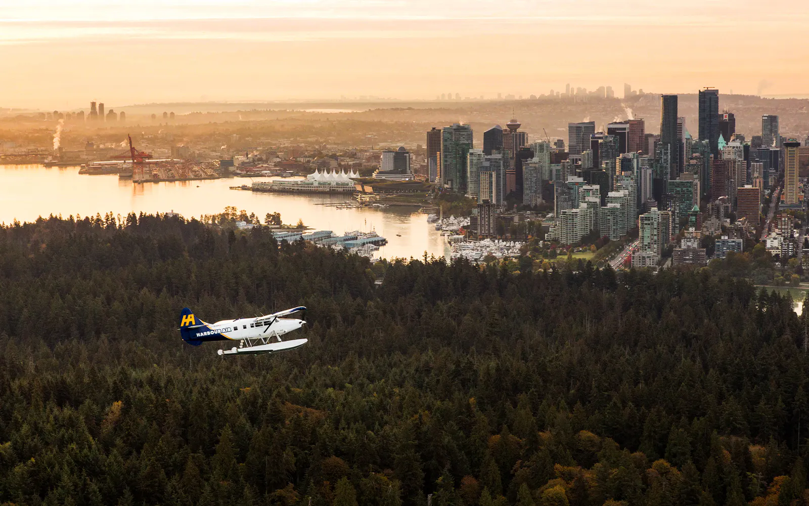 Seaplane flying over lush forests with Vancouver skyline in the background during scenic tour.